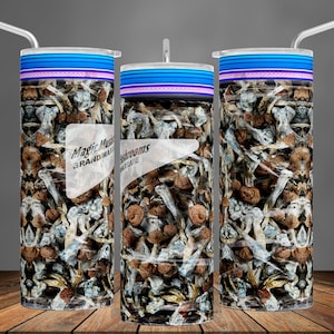 May include: A stainless steel tumbler with a blue and pink striped lid and a design of brown and white mushrooms. The tumbler has the text "Magic Mushrooms" and "Brand Name" on it.