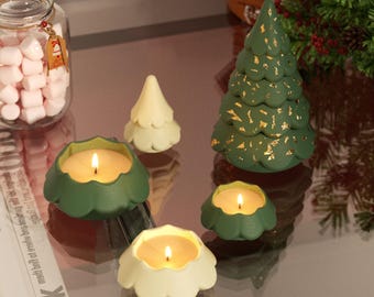 May include: A collection of Christmas-themed candles and decorations. The image features green and cream-colored tree-shaped candles, along with candles in green and cream-colored floral-shaped holders. A large green tree candle with gold accents is also present.