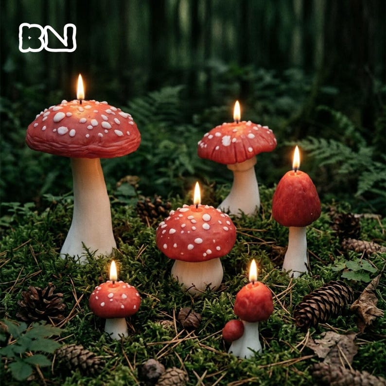 May include: Six mushroom-shaped candles of varying sizes, each featuring a red cap with white spots and a white stem. Each candle is lit with a small flame. The candles are arranged in a cluster, with the largest on the left and smaller ones.