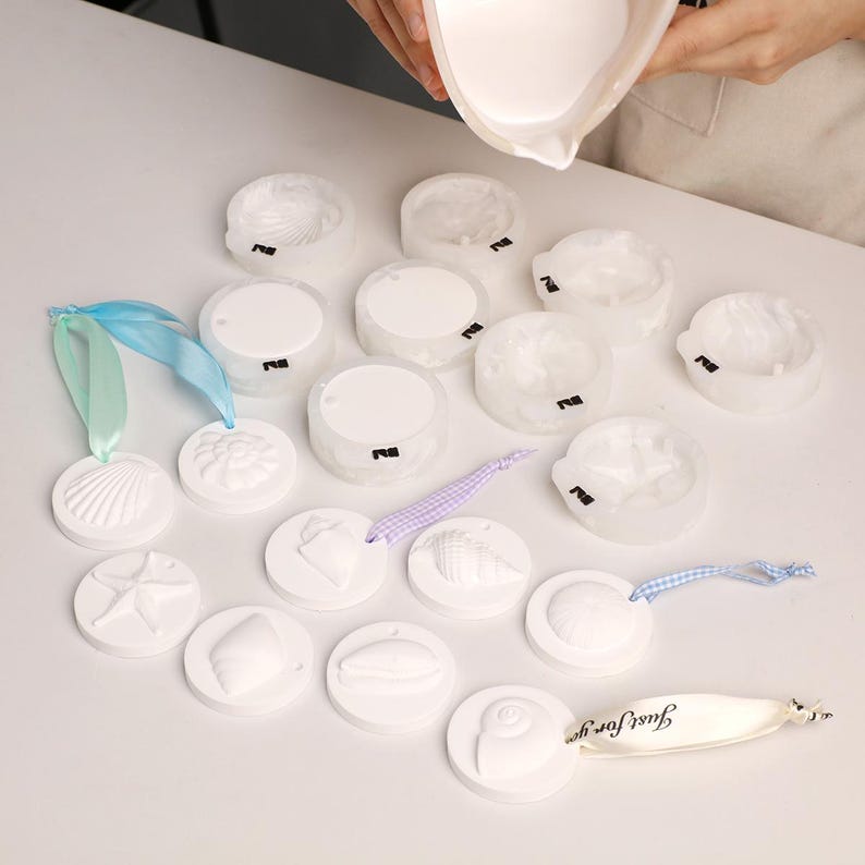 Op de afbeelding: Witte, ronde ornamenten met schelpmotieven, linten en een "Just for you" label. De ornamenten tonen verschillende zeedierontwerpen en worden gevuld met een witte vloeistof. Ideaal voor kustdecoratie of knutselprojecten.