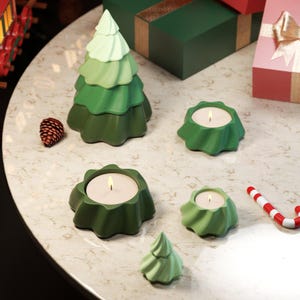 Può includere: Un set di cinque portacandele in ceramica verde a forma di albero di Natale. Il portacandele più grande è a forma di albero di Natale e gli altri quattro sono a forma di stella. Ogni portacandele contiene una piccola candela.
