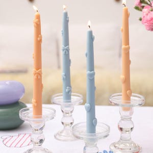 Witness the beauty of four burning Ribbon Bow Taper Candles individually placed on glass candle holders, casting a mesmerizing glow.