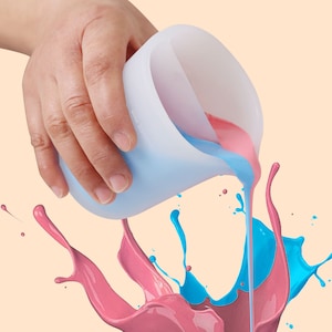 May include: A hand pouring blue and pink paint from a silicone cup, creating a splash of color.