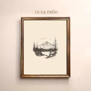 May include: A black and white line drawing of a mountain scene with a lake in the foreground. The drawing is framed in a brown wooden frame. The text "11:14 ratio" is printed above the frame.