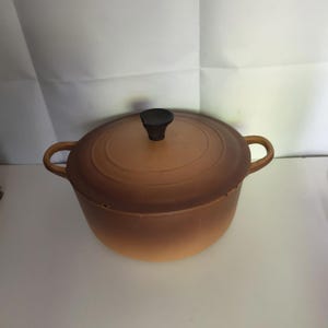 Puede incluir: Una taza de cerámica blanca con un asa negra y el texto "But First, Coffee" en un estilo manuscrito. La taza está sobre una superficie blanca. La taza mide aproximadamente 10 cm de alto.