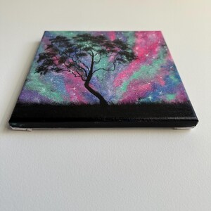 Peut inclure: Une peinture d'un arbre en silhouette sur un fond de galaxie color&eacute;. La galaxie est peinte dans des tons de rose, violet et vert avec des &eacute;toiles blanches.
