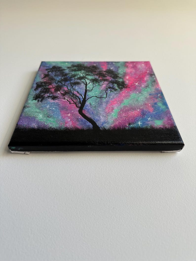 Peut inclure: Une peinture d'un arbre en silhouette sur un fond de galaxie color&eacute;. La galaxie est peinte dans des tons de rose, violet et vert avec des &eacute;toiles blanches.