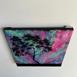 Peut inclure: Une peinture repr&eacute;sentant un arbre en silhouette sur fond de galaxie color&eacute;e. La galaxie est peinte dans des tons de rose, vert et bleu avec des &eacute;toiles blanches.