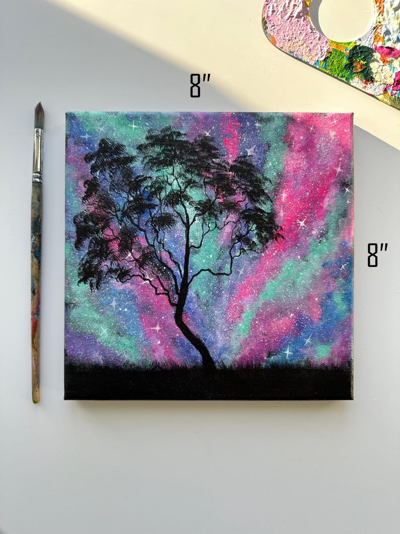 Peut inclure: Une peinture sur toile de 20,3 x 20,3 cm repr&eacute;sentant un arbre en silhouette devant une galaxie color&eacute;e aux teintes roses, violettes et vertes. La galaxie est parsem&eacute;e d'&eacute;toiles blanches.