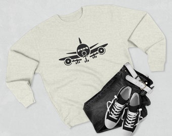 May include: A heather grey sweatshirt with a black airplane silhouette printed on the front. The sweatshirt is laid flat on a white surface with a pair of black sneakers and blue jeans.