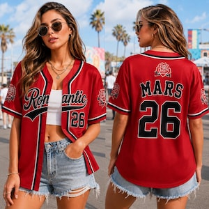 May include: A red baseball jersey featuring black and white trim, the word Romantic on the front, the word Mars on the back, the number 26 on both sides, and rose graphics on the sleeves and back. The jersey is worn over a white crop top.