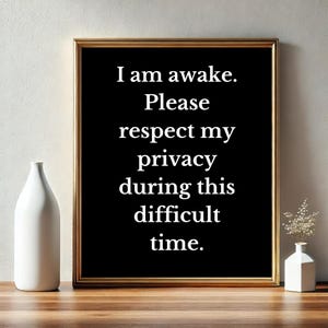 May include: Black and gold framed print with white text that reads "I am awake. Please respect my privacy during this difficult time."