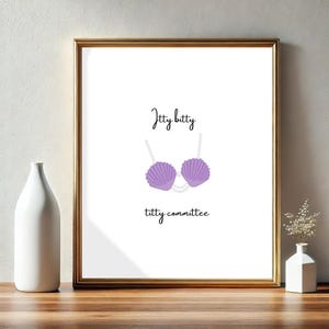 Op de afbeelding: Een witte ingelijste print met de tekst "itty bitty titty committee" en een paarse schelpbeha met een parelketting.