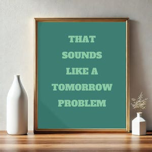 May include: A framed print with a teal background and white text that reads "THAT SOUNDS LIKE A TOMORROW PROBLEM".