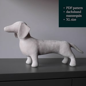 Könnte beinhalten: Hellgraue Dackel-Mannequin in XL-Größe. Das hundeförmige Mannequin ist aus weichem Stoff gefertigt und steht auf einer dunkelgrauen Oberfläche. Das Bild enthält den Text "PDF pattern dachshund mannequin XL size."