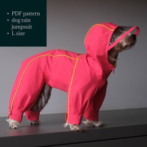 Pode incluir: Um macacão de chuva rosa brilhante para cães com detalhes amarelos e uma viseira transparente. O macacão cobre o corpo e as pernas do cão e tem um capuz. O texto na imagem diz "PDF pattern", "dog rain jumpsuit" e "L size".