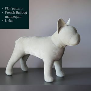 Puede incluir: Un maniquí de Bulldog Francés gris claro en talla L. La forma de perro de peluche está de pie sobre una superficie gris oscuro contra un fondo gris claro. El texto a la izquierda dice "PDF pattern", "French Bulldog mannequin" y "L size".