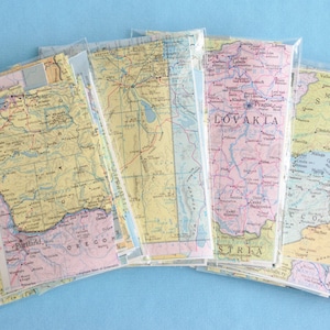 May include: A set of six vintage maps in plastic sleeves. The maps are in various colors and show different regions of the world. The maps are labeled with the names of the countries and regions they depict.
