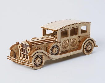 Könnte beinhalten: Ein Holzmodell eines klassischen Autos mit aufwendigen Details. Das Auto hat eine hellbraune Farbe mit sichtbaren Rädern, Fenstern und einem detaillierten Frontgrill. Das Modell ist zum Zusammenbauen konzipiert und zeigt die Handwerkskunst des Designs.
