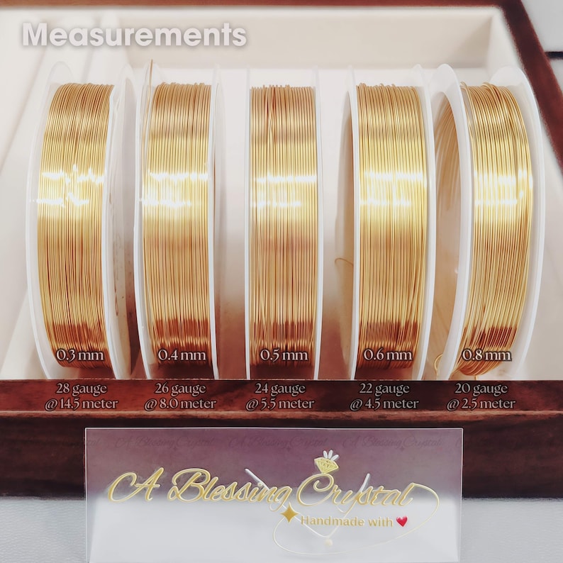 May include: Five spools of gold wire in different gauges, labeled with their thickness in millimeters and gauge number. The spools are arranged from left to right in order of increasing thickness. The text "Measurements" is at the top of the image. The text "A Blessing Crystal Handmade with" is at the bottom of the image.