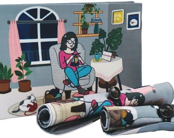 May include: A gray and white tote bag with a colorful illustration of a woman knitting in a cozy living room. The bag has a zipper closure and comes with three matching fabric rolls, each with a button closure.