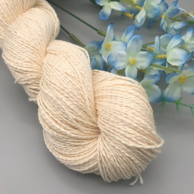 Peut inclure: Une pelote de fil de coton blanc naturel, parfaite pour le tricot ou le crochet. Le fil est doux et moelleux, et il a un l&eacute;ger &eacute;clat.