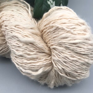 May include: A skein of off-white yarn with a fuzzy texture.