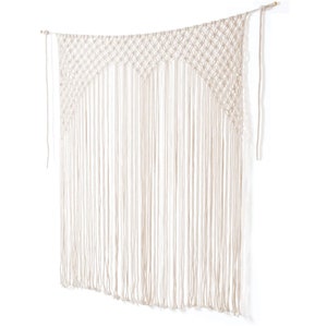 Op de afbeelding: Een macramé wandkleed in een natuurlijke off-white kleur. Het bovenste gedeelte heeft een geometrisch ruitpatroon, met lange, verticale franjes eronder. Het stuk is opgehangen aan een houten deuvel, wat een boheems decoratief element creëert.