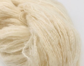 May include: A skein of soft, white yarn. The yarn is made of natural fibres and has a fluffy texture.