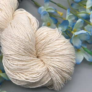 May include: A skein of natural white cotton yarn, perfect for knitting or crocheting. The yarn is soft and smooth, and it has a natural, rustic look.