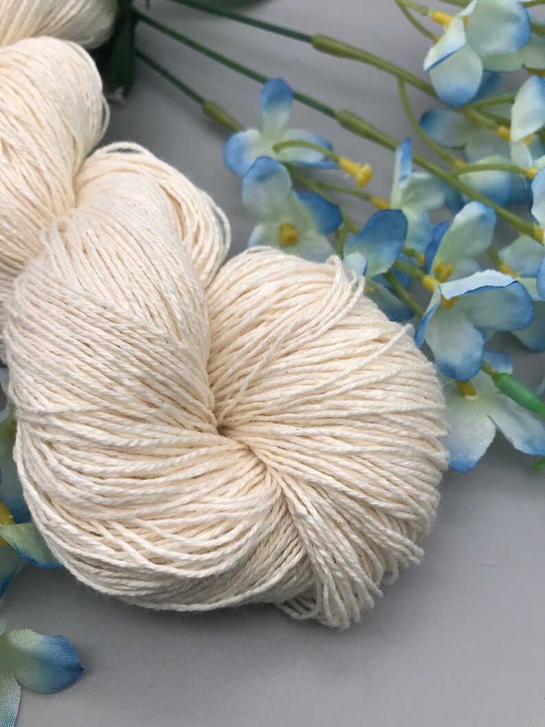 May include: A skein of natural white cotton yarn, perfect for knitting or crocheting. The yarn is soft and smooth, and it has a natural, rustic look.