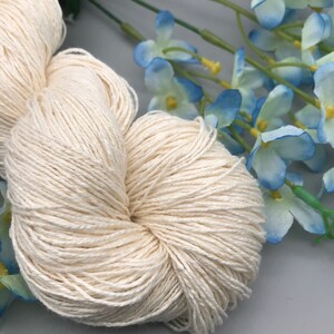 May include: A skein of natural white cotton yarn, perfect for knitting or crocheting. The yarn is soft and smooth, and it has a subtle sheen.