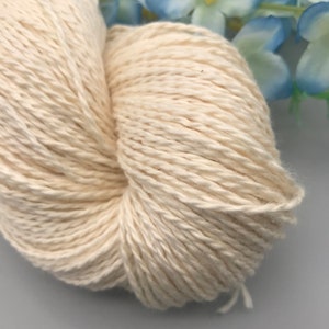Peut inclure: Un gros plan d'une pelote de fil de coton blanc naturel. Le fil est doux et moelleux, et il est parfait pour le tricot ou le crochet.