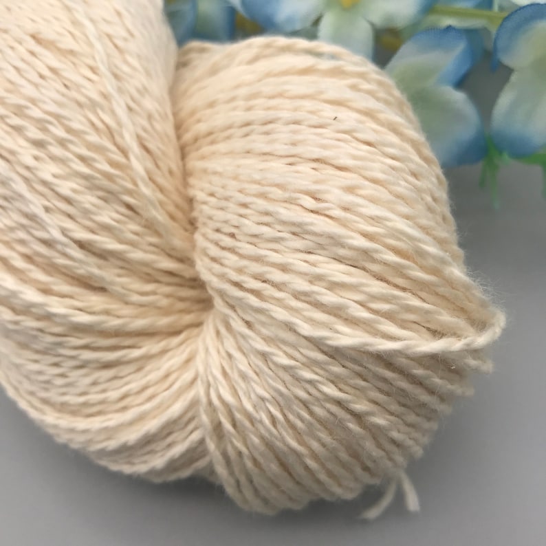 Peut inclure: Un gros plan d'une pelote de fil de coton blanc naturel. Le fil est doux et moelleux, et il est parfait pour le tricot ou le crochet.