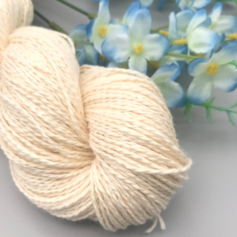 Peut inclure: Un gros plan d'une pelote de fil de coton blanc naturel. Le fil est doux et moelleux, et il est parfait pour le tricot ou le crochet.
