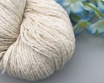 May include: A skein of off-white yarn, made of natural fibers, is shown in a close-up view. The yarn is soft and fluffy, and it is perfect for knitting or crocheting.