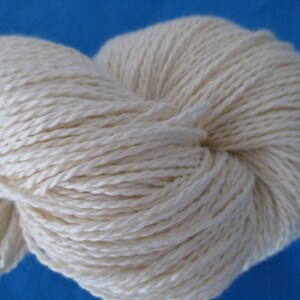 Peut inclure: Une pelote de fil blanc naturel, compos&eacute;e de fibres douces et moelleuses. Le fil est torsad&eacute; et textur&eacute;, cr&eacute;ant un aspect et une sensation uniques.