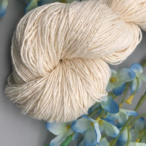 May include: A skein of natural white cotton yarn, perfect for knitting or crocheting. The yarn is soft and smooth, and it has a subtle sheen.