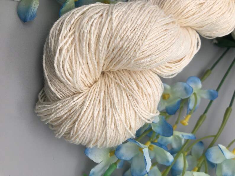 May include: A skein of natural white cotton yarn, perfect for knitting or crocheting. The yarn is soft and smooth, and it has a subtle sheen.