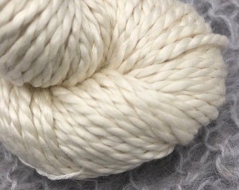 May include: A close-up of a skein of white yarn. The yarn is soft and fluffy, and it is perfect for knitting or crocheting.