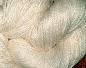 Peut inclure: Gros plan sur une pelote de fil de couleur crème. Le fil est doux et moelleux, idéal pour le tricot ou le crochet.