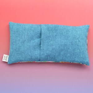 May include: A blue linen eye pillow with a floral print on the back. The pillow has a seam down the center and a small white tag with the text "Made with love in California".