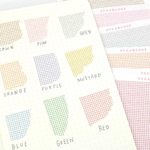 May include: A collection of grid-patterned adhesive paper strips in various colors including brown, pink, grey, orange, purple, mustard, blue, green, and red. Each strip is labeled with its color name and features the brand name SUGARLOOP.
