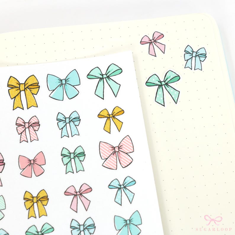 May include: A sheet of stickers with various colored bows. The bows are in shades of pink, blue, green, and yellow. The stickers are on a white background.