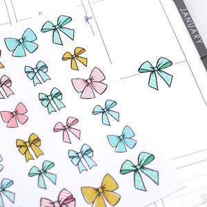 May include: A sheet of colorful bow stickers in various colors, including pink, blue, yellow, and green. The stickers are perfect for adding a touch of whimsy to planners, journals, and other paper crafts.
