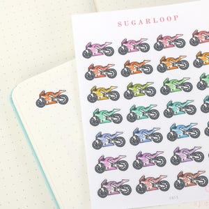 May include: A sheet of colorful motorcycle stickers in various colors, including pink, orange, yellow, green, teal, blue, purple, and brown. The stickers are arranged in rows and columns on a white background. The word "SUGARLOOP" is printed at the top.