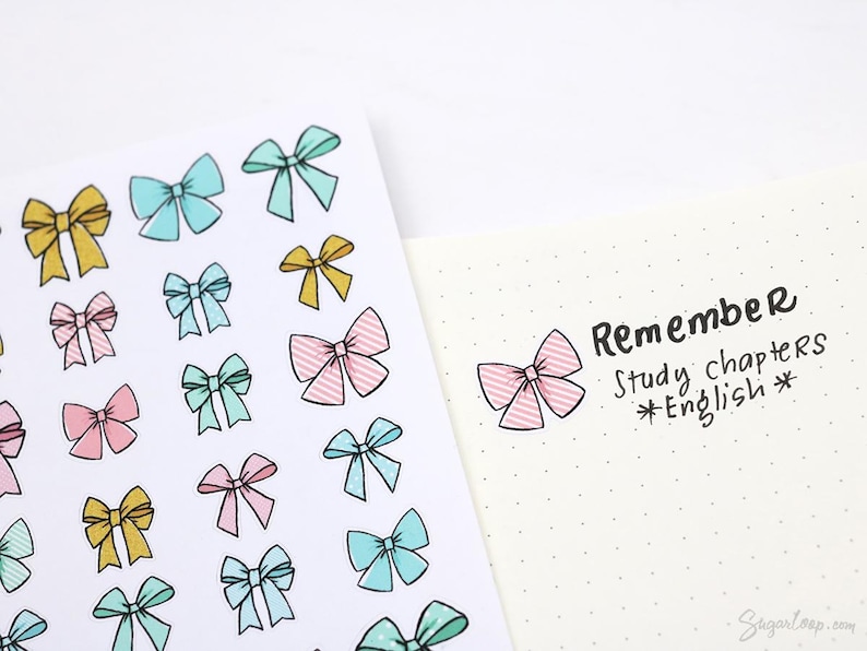 May include: A sheet of colorful bow stickers with a pink, blue, and yellow color scheme. The stickers are arranged in a grid pattern. The sheet is next to a white page with black text that reads "Remember Study chapters *English*"