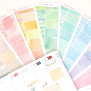 May include: A collection of watercolor stickers and a planner. The stickers feature rectangular color swatches in various pastel shades, including pink, blue, green, and yellow. The planner is open, displaying a calendar layout with decorative elements.