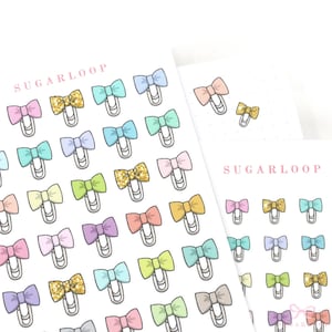 May include: A sheet of colorful bow-shaped stickers with a glitter accent. The stickers are arranged in a grid pattern and feature the text "Sugarloop" at the top of the sheet.