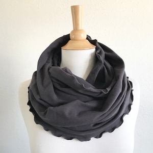 May include: A charcoal gray infinity scarf with a ruffled edge.